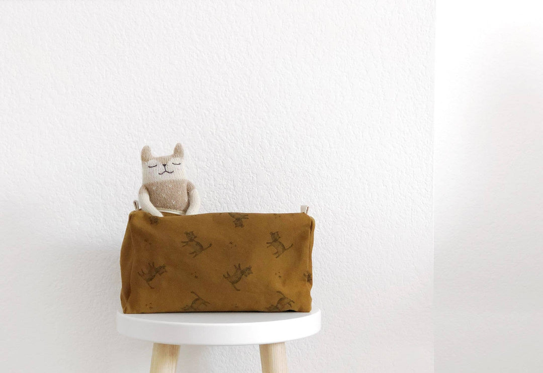 Children's toiletry bag featuring a cat print in cumin color, displayed with a cute toy on a stool.