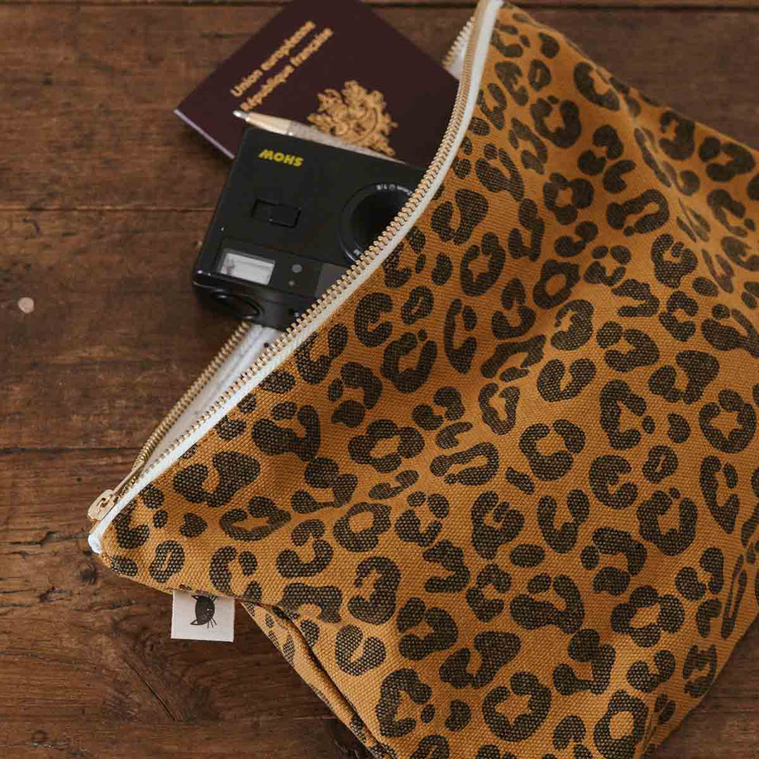 Lili Flat Pouch in leopard caramel print with camera and passport for travel essentials.