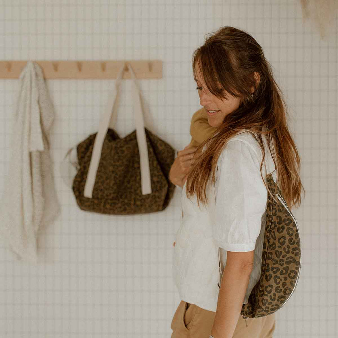 Woman wearing BUM BAG GRAOU OLIVE in leopard print, showcasing its versatile design against a stylish backdrop.