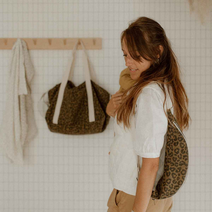 Woman wearing BUM BAG GRAOU OLIVE in leopard print, showcasing its versatile design against a stylish backdrop.
