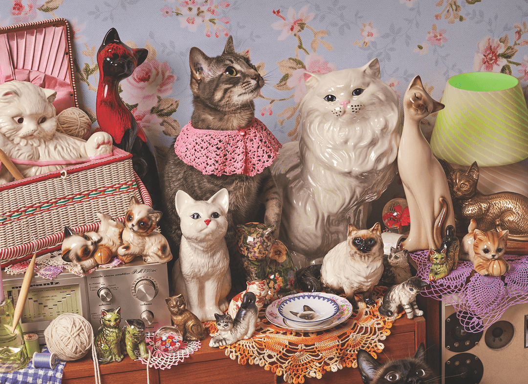 Vintage-style cat figurines and decor with floral wallpaper background.