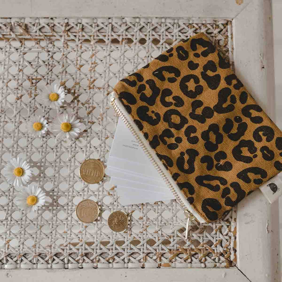Marie Purse Graou Caramel in leopard print, perfect for organizing small accessories, displayed with coins and flowers.