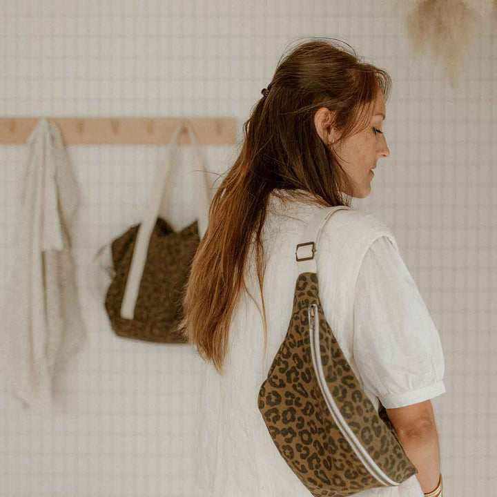 Woman wearing BUM BAG GRAOU OLIVE leopard print bag as a crossbody, showcasing hands-free style and organization.