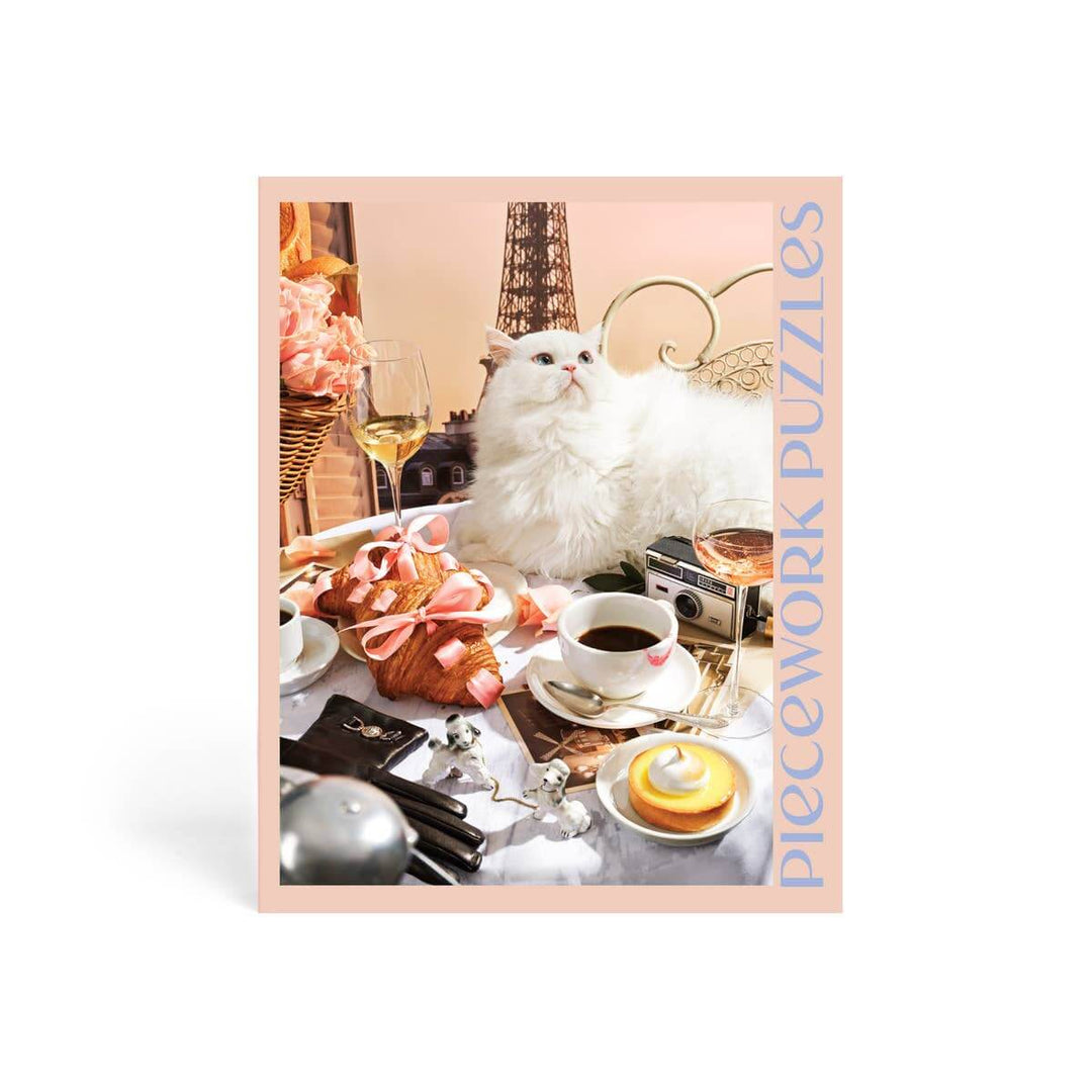 Jigsaw puzzle box featuring a grumpy cat surrounded by Parisian items like baguettes and pastries, with Piecework Puzzles branding.