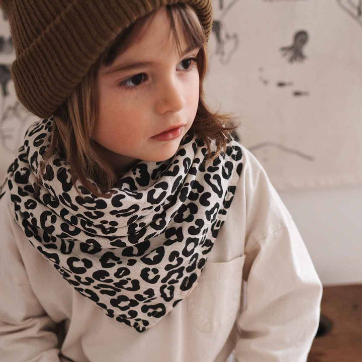 Child wearing a greige leopard print scarf, showcasing stylish and cozy design for kids.
