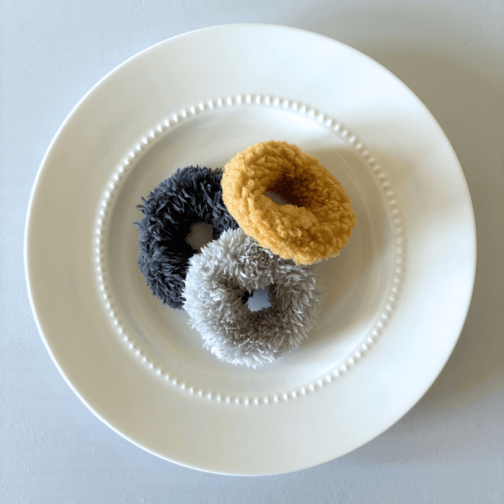 Three plush mini donut cat toys in assorted colors on a white plate, designed for feline entertainment and long-lasting fun.