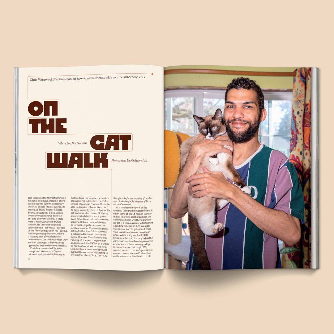 Man holding a cat next to an open Catnip Magazine featuring the article "On The Cat Walk"