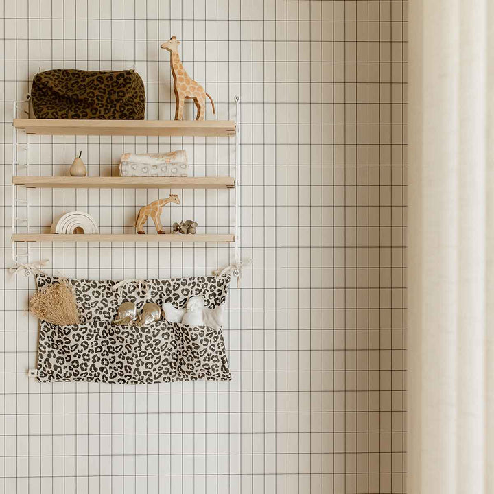 Stylish Vic Toiletry Bag in olive leopard print on modern shelving with decorative giraffe toys.