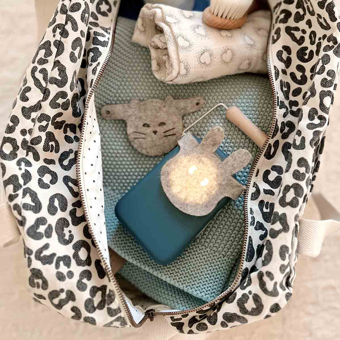 Interior view of leopard print tote bag with folded items and playful accessories.