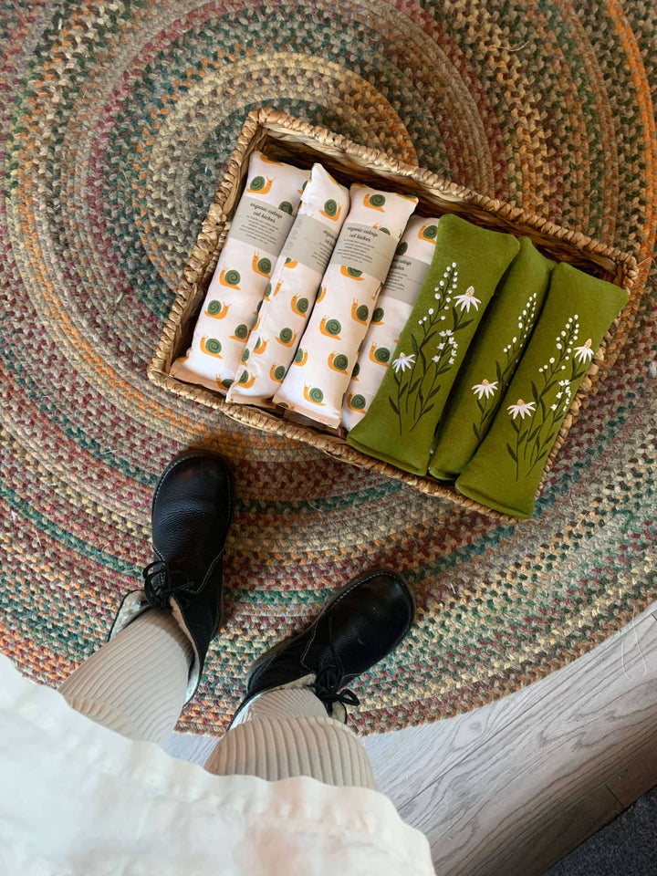 Basket of Daisies of Denmark woolly organic catnip kickers on a textured rug, showcasing unique embroidery and colors.