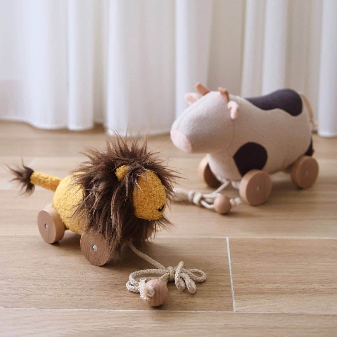 Adorable plush lion and cow pull toys for kids, encouraging crawling and walking during playtime.