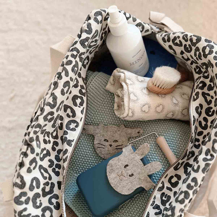 Open tote bag showing leopard print interior with baby supplies and cosmetics inside.