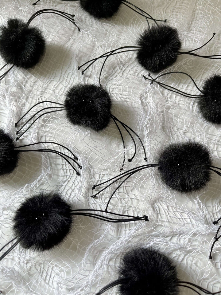 Black fluffy tarantula wand toys on a white surface, perfect for engaging cat playtime during Halloween and beyond.