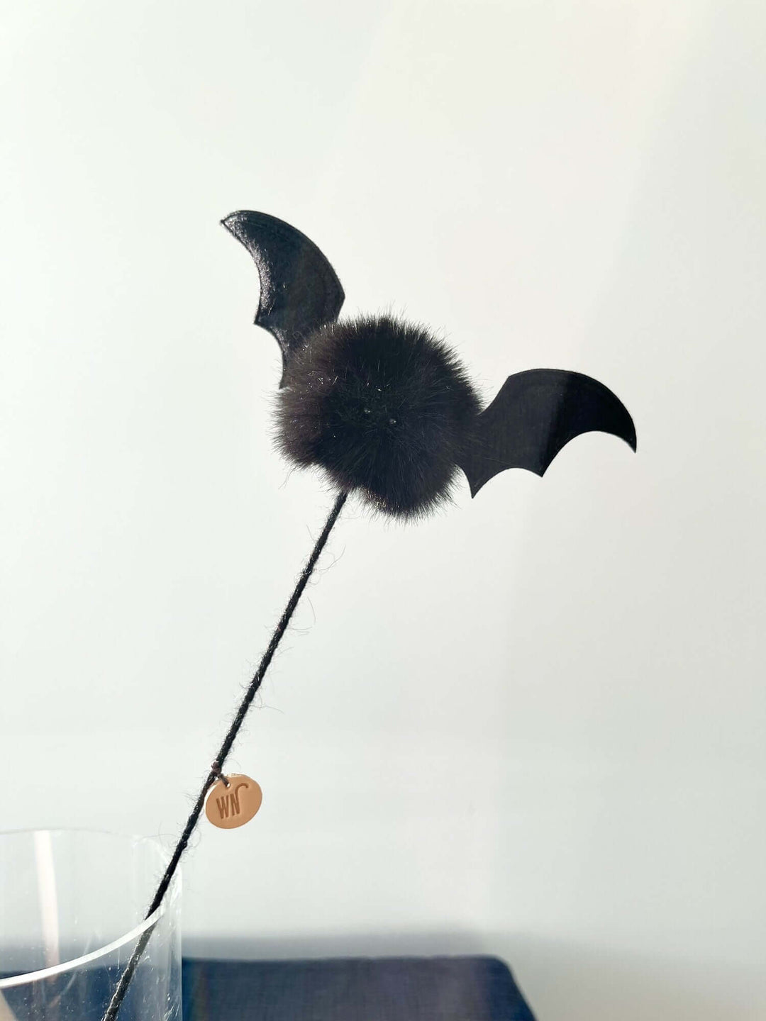 Black vampire bat cat toy on a stick with furball body and felt wings, handmade in South Korea, stimulates feline curiosity.